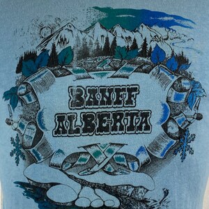 K&ouml;nnte beinhalten: Ein Vintage-T-Shirt in Blau mit einem grafischen Aufdruck einer Bergszene und dem Text "Banff Alberta".