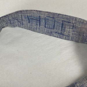 May include: A close-up of a blue and white woven fabric belt with the word "HUE" written in blue.