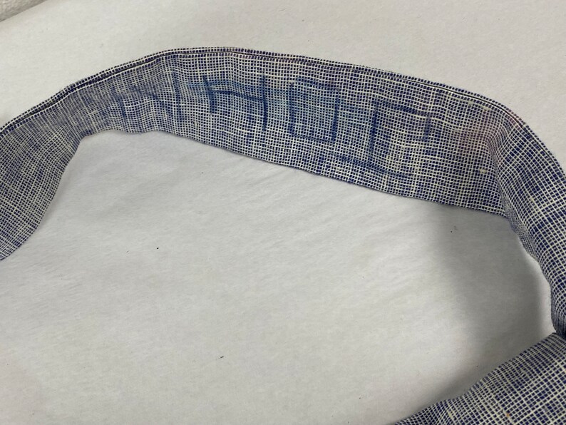 May include: A close-up of a blue and white woven fabric belt with the word "HUE" written in blue.