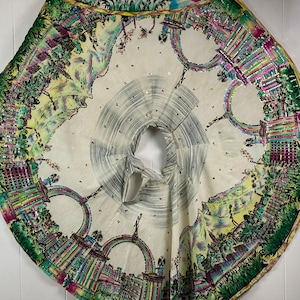 May include: A white fabric circle with a colorful, detailed design of a city skyline and arches. The fabric is decorated with small, iridescent sequins.