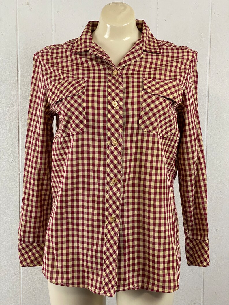May include: A long-sleeved button-down shirt with a red and white gingham pattern. The shirt has two chest pockets and a classic collar.
