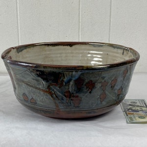 May include: A large, brown and white ceramic bowl with a mottled glaze and a design of brown and blue leaves. The bowl is approximately 25 cm in diameter.