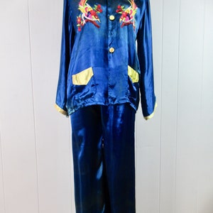 May include: A blue satin pajama set with gold trim and embroidered birds. The top has a button-up front and two pockets. The pants have a straight leg.