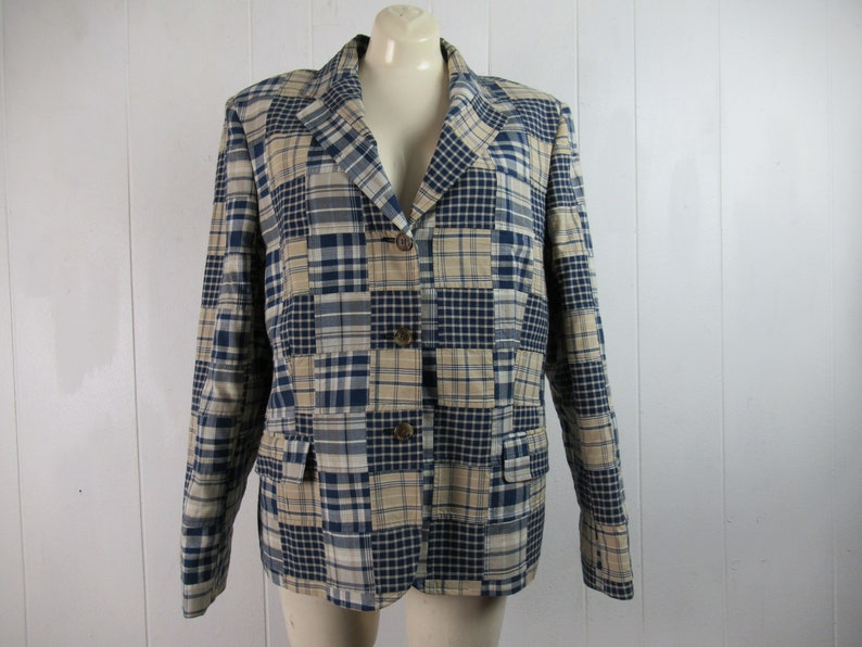 May include: A blue and beige plaid blazer with a button closure. The blazer is made of a patchwork fabric with different sized squares.