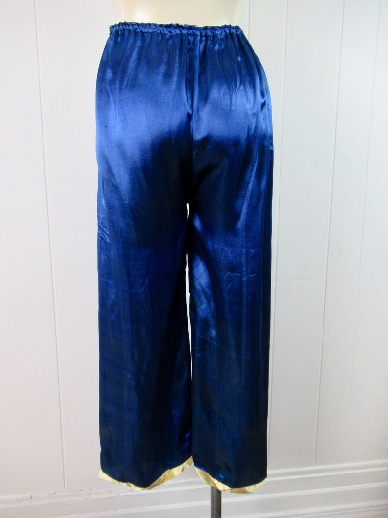 May include: Blue satin pajama pants with a gold trim around the bottom.