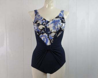 Puede incluir: Un traje de baño azul marino con estampado floral en la parte superior. El traje de baño tiene un detalle anudado en la cintura.