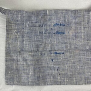May include: A blue linen bag with a strap. The bag has handwritten text on it, including "Merrimack" and "N".