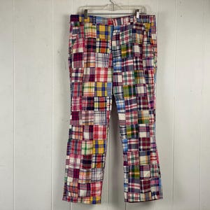 May include: Patchwork pants with a multi-colored plaid pattern in shades of red, blue, yellow, and white.