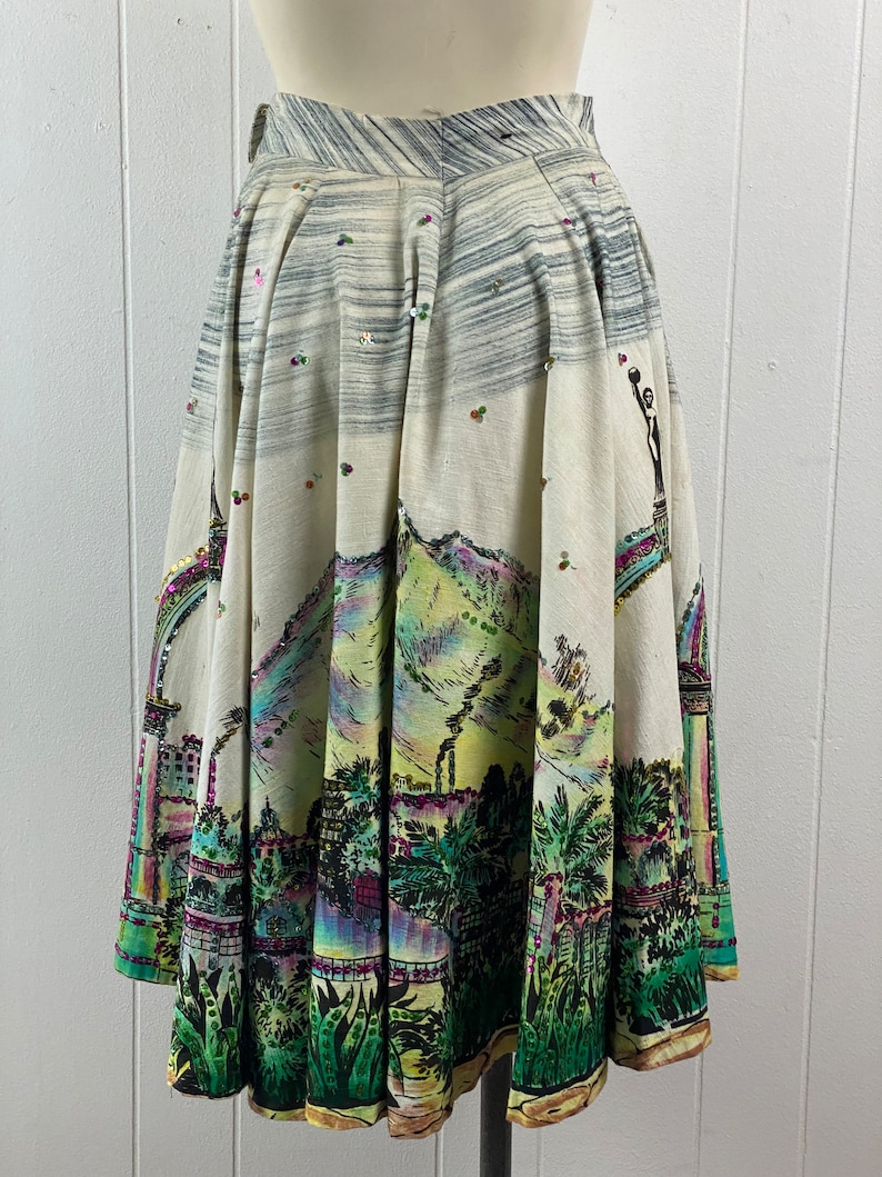 May include: A white skirt with a colorful city scene print and sequins. The skirt is full and has a gathered waist.