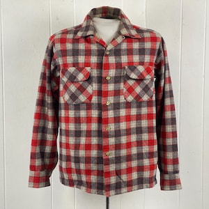 May include: A long-sleeved, button-down shirt with a red, brown, and tan plaid pattern. The shirt has two chest pockets and a collared neckline. The shirt is displayed on a mannequin against a white background.