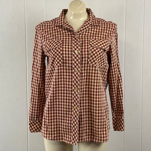 May include: A long-sleeved button-down shirt with a red and cream gingham pattern. The shirt has two chest pockets and a classic collar.