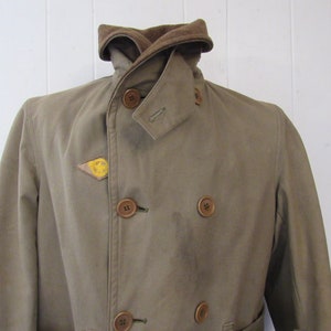 May include: A brown double-breasted jacket with a corduroy collar and a yellow smiley face patch on the left side.