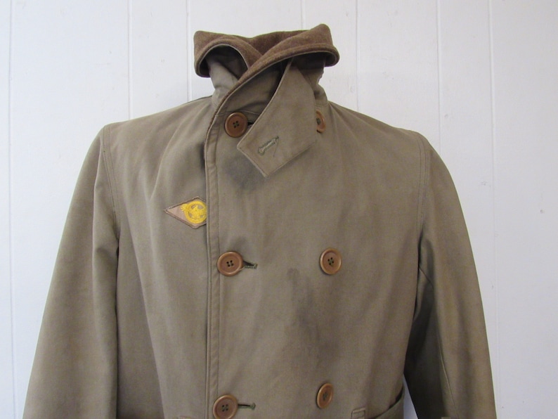 May include: A brown double-breasted jacket with a corduroy collar and a yellow smiley face patch on the left side.