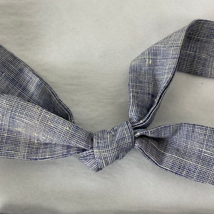 May include: A blue and white bow tie made of a textured fabric. The bow tie is tied in a knot and is ready to be worn.