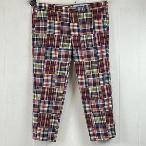 May include: Pants featuring a patchwork design composed of various plaid fabric squares in shades of red, navy blue, yellow, and white. The trousers include a waistband with belt loops, a front button closure, and a classic straight-leg cut.