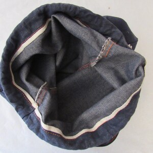 K&ouml;nnte beinhalten: Innenansicht einer dunkelblauen Jeans-Tasche mit wei&szlig;em und orangefarbenem Besatz. Die Tasche ist aus einem dicken, strapazierf&auml;higen Stoff gefertigt und hat ein ger&auml;umiges Innenleben.