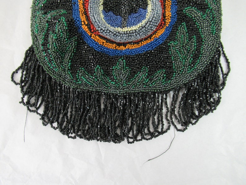 Puede incluir: Un bolso negro de cuentas con un dise&ntilde;o verde y multicolor y un fondo de flecos.