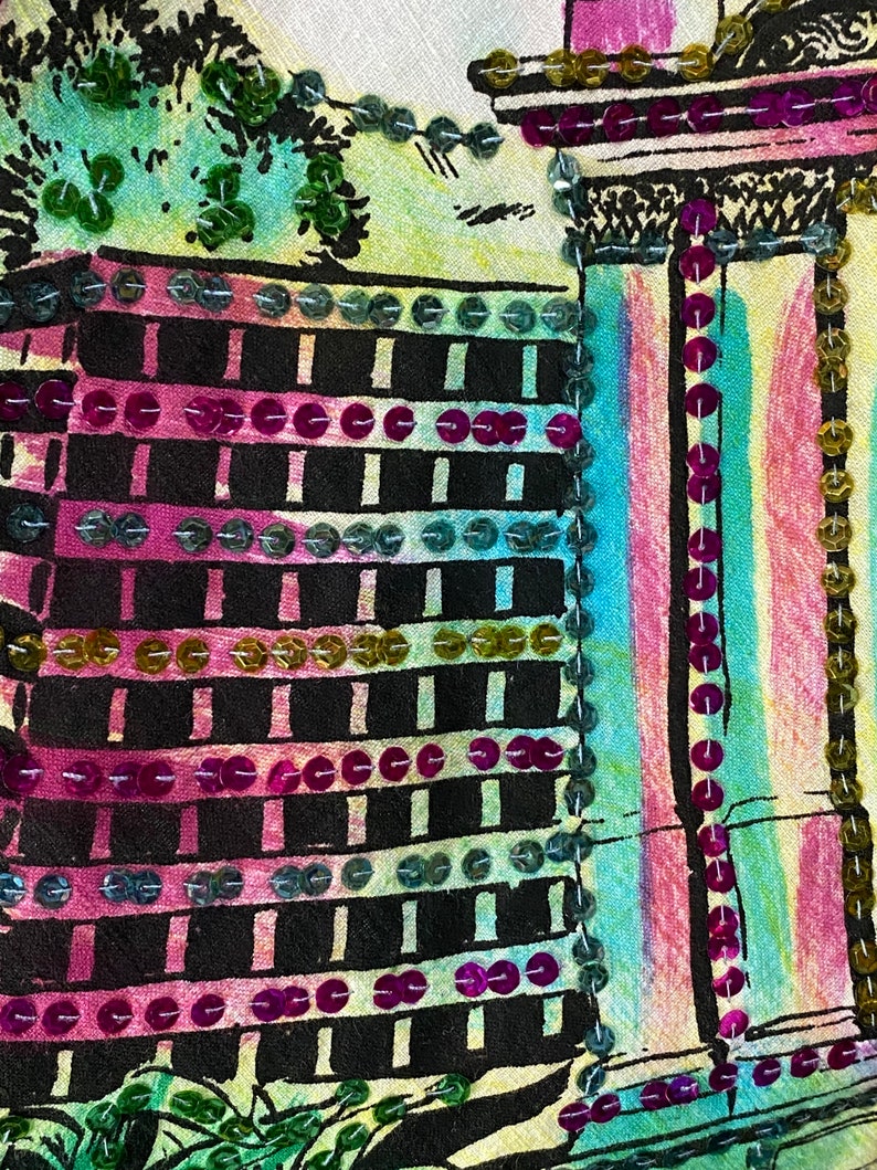 May include: A close-up of a fabric with a colorful design of a building with a black and white grid pattern. The fabric is decorated with sequins in various colors, including pink, green, and gold.