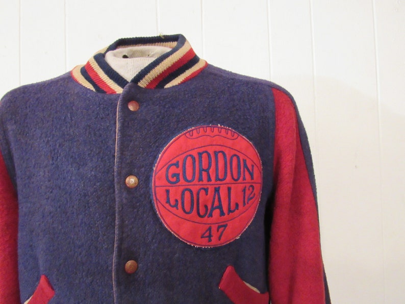 May include: A navy blue and red varsity jacket with a red patch on the left side that says "Gordon Local 12 47".