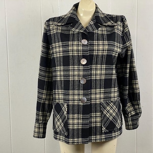 May include: A vintage black and cream plaid jacket with a collared neckline, three large buttons, and two front pockets. The long-sleeved jacket is displayed on a mannequin.