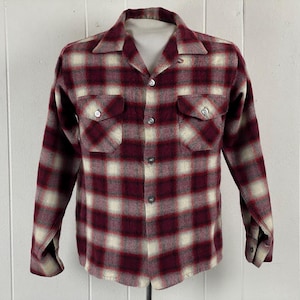 May include: A long-sleeved flannel shirt with a red and white plaid pattern. The shirt has a collared neckline and a button-up front.