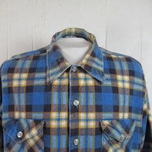以下が含まれることがあります： ボタンダウンカラーと長袖の青、黄、茶色の格子柄のフランネルシャツ