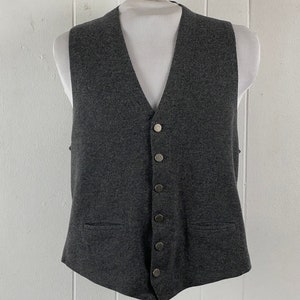 Può includere: Un gilet di maglia grigio scuro con scollo a V e cinque bottoni argentati sul davanti.