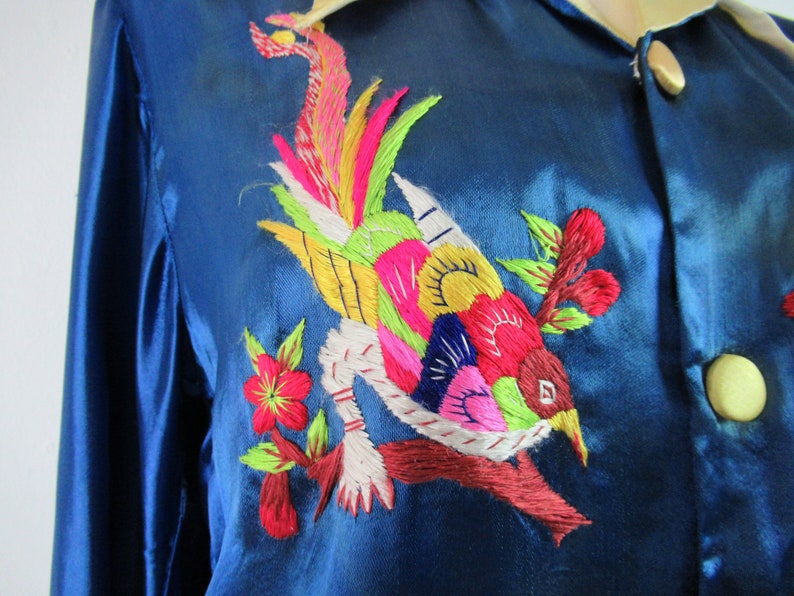 May include: A blue silk shirt with colorful embroidered bird and floral designs.