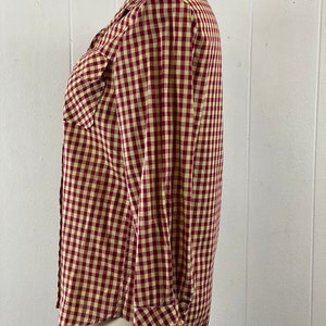 May include: A red and white gingham button-up shirt with long sleeves and a single chest pocket.