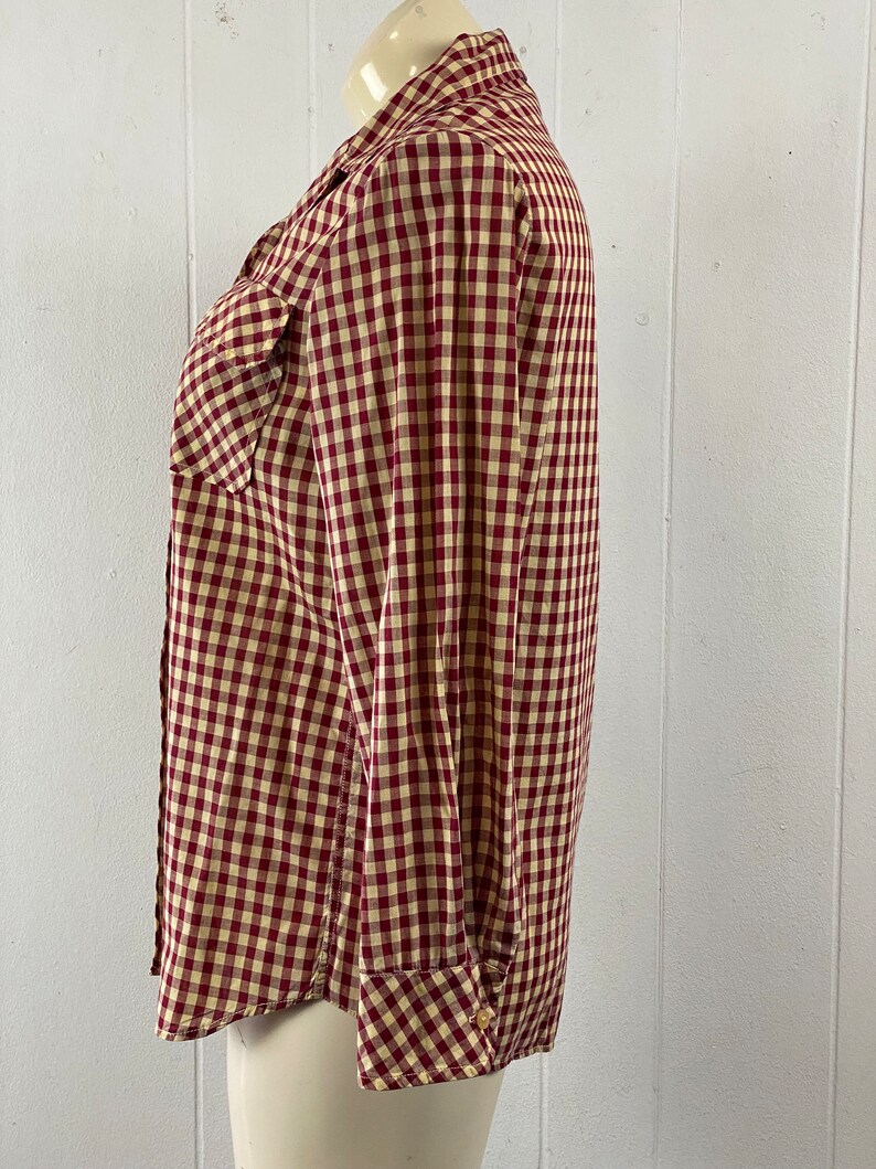 May include: A red and white gingham button-up shirt with long sleeves and a single chest pocket.