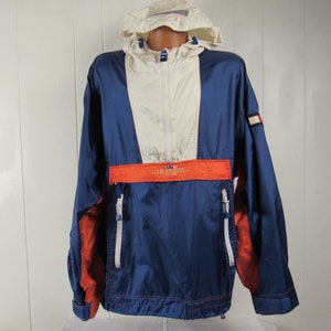 May include: A blue, white, and orange hooded jacket with a zipper closure. The jacket has a Tommy Hilfiger logo on the sleeve.