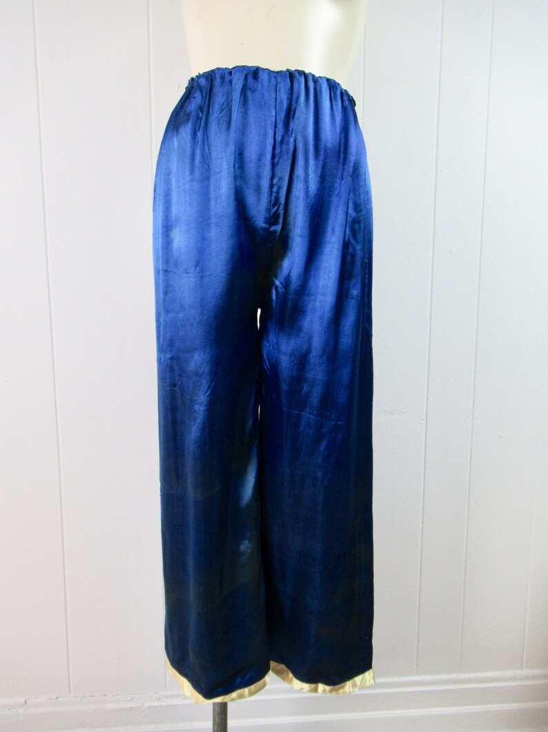 May include: Blue satin pants with a gold trim around the waist and legs.