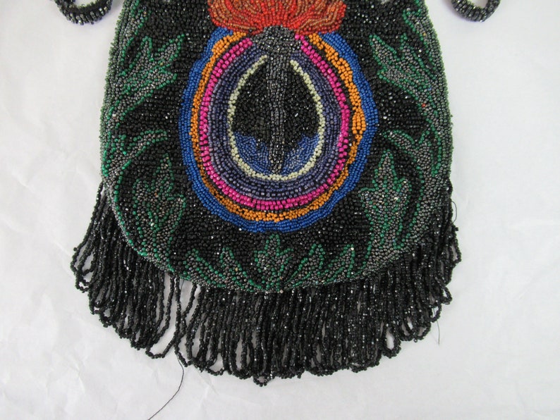 Puede incluir: Un bolso negro de cuentas con un dise&ntilde;o floral colorido y un fondo de flecos.