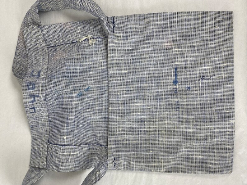 May include: A blue and white fabric bag with a strap. The bag has a flap that folds over and closes with a button. The bag is marked with the letters "L" and "H" on the strap.