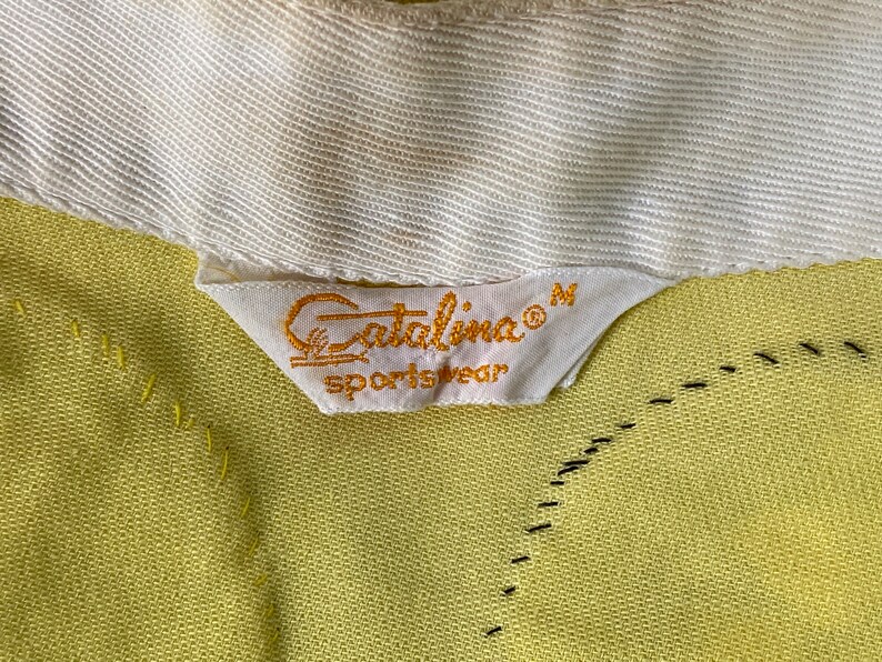 May include: A yellow Catalina sportswear label with the text "Catalina&reg; Sportswear" and the size "M" in white.