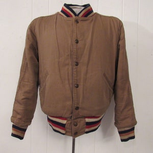 May include: A brown bomber jacket with a white, red, and blue striped collar and cuffs.