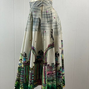May include: A white, full-skirted skirt with a colorful city scene print and sequins. The skirt has a back zipper and a high waist.
