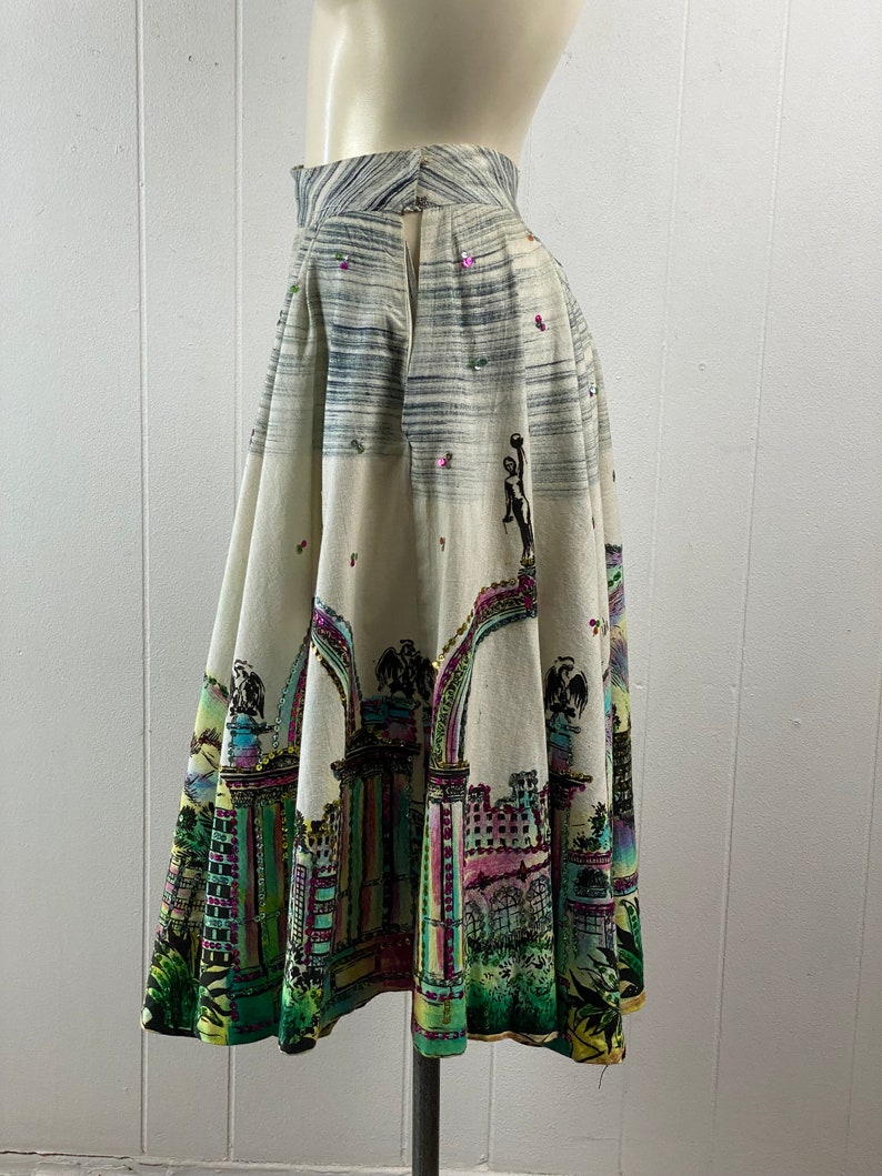 May include: A white, full-skirted skirt with a colorful city scene print and sequins. The skirt has a back zipper and a high waist.