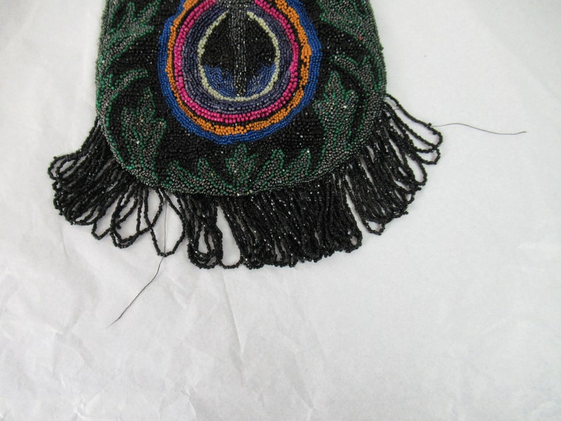 Puede incluir: Un bolso de cuentas negras con un dise&ntilde;o circular de colores y una franja de cuentas negras.