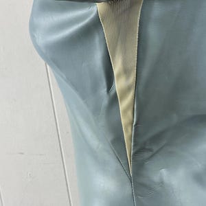 K&ouml;nnte beinhalten: Ein hellblaues Kunstlederkleid mit einem cremefarbenen Einsatz auf der R&uuml;ckseite.