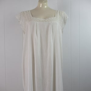 Puede incluir: Un camis&oacute;n blanco de algod&oacute;n con ribete de encaje alrededor del escote y las mangas. El camis&oacute;n tiene un escote cuadrado y un corte holgado.