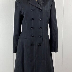 May include: A black pinstripe double-breasted dress with a long skirt and long sleeves.