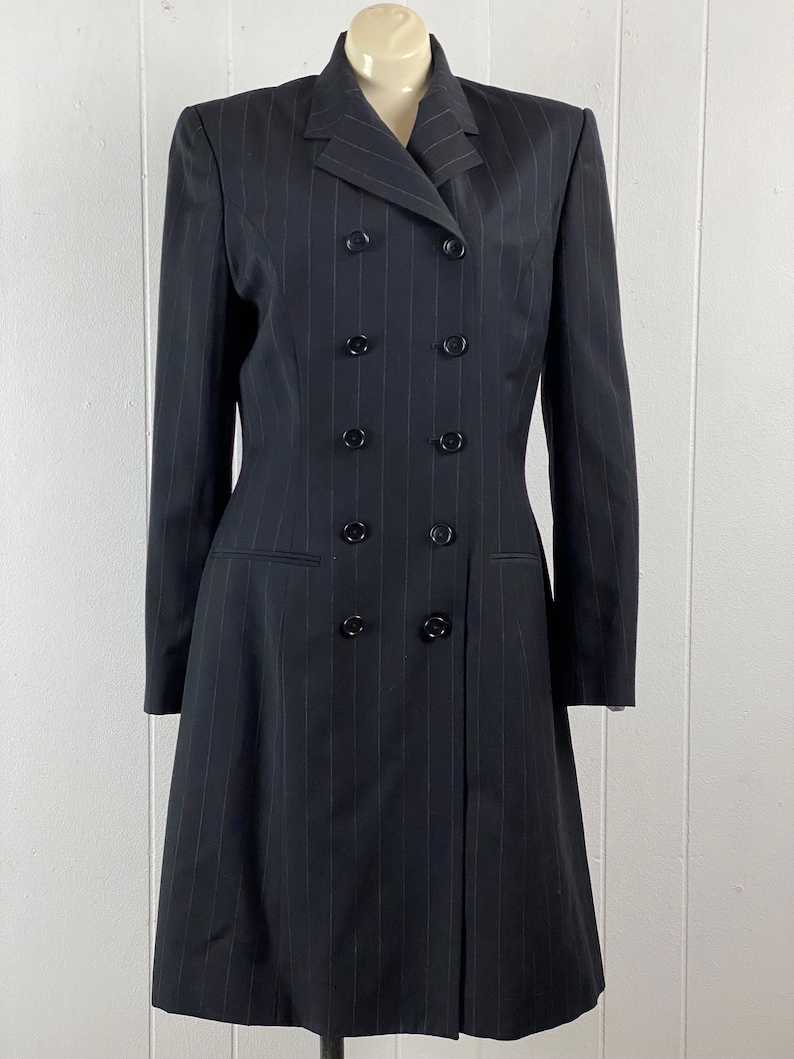 May include: A black pinstripe double-breasted dress with a long skirt and long sleeves.