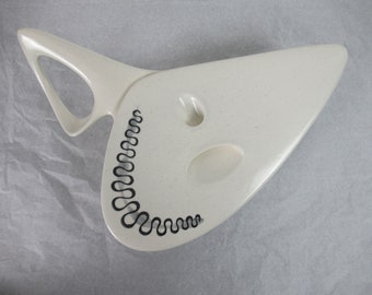 May include: White ceramic serving tray with a unique, abstract shape and a black wavy design. The tray has two indentations for serving.