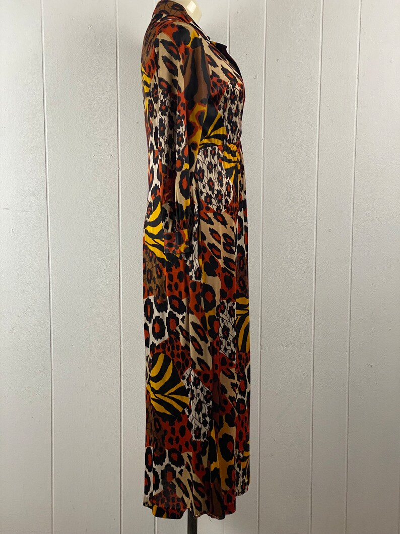 Puede incluir: Un vestido de manga larga con estampado de animales en marr&oacute;n, naranja, amarillo y negro. El vestido tiene cuello y cierre de botones en la parte delantera.