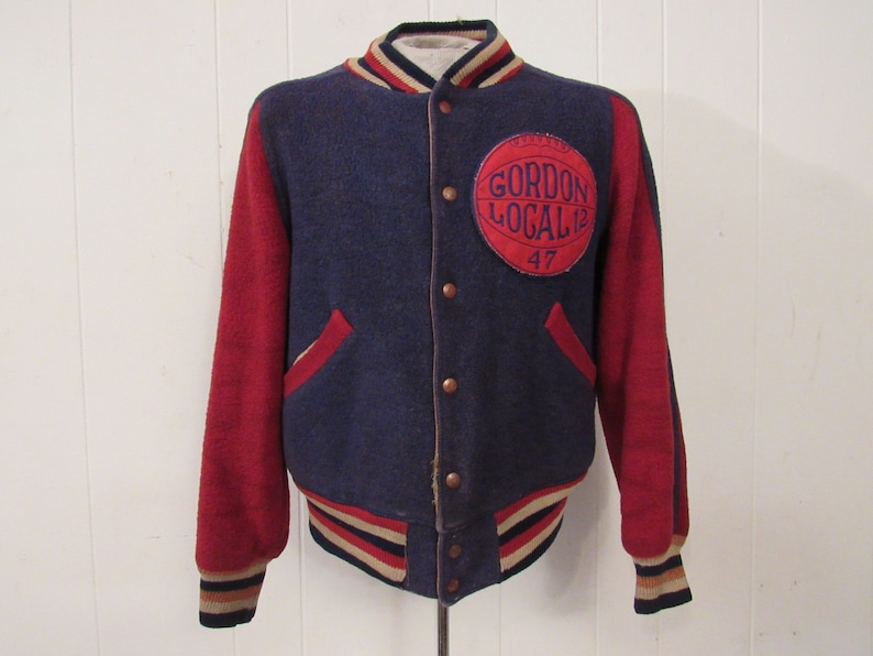 May include: A vintage blue and red varsity jacket with a large circular patch on the left chest that reads "Gordon Local 12 47".
