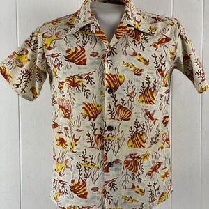 May include: A short-sleeved button-up shirt with a white background and a pattern of red and yellow fish and coral.