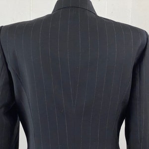 May include: A black pinstripe blazer with a single-breasted closure. The blazer has a classic fit and a smooth, textured fabric.