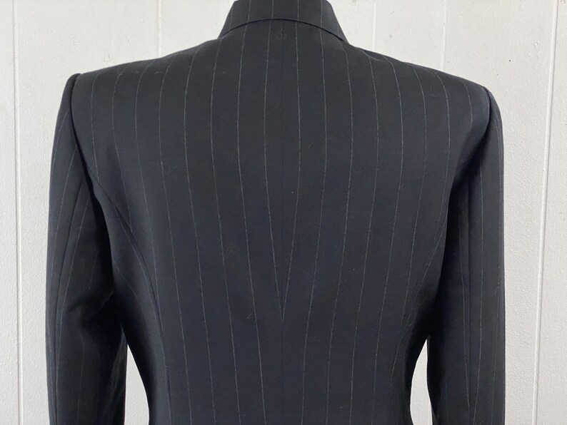 May include: A black pinstripe blazer with a single-breasted closure. The blazer has a classic fit and a smooth, textured fabric.