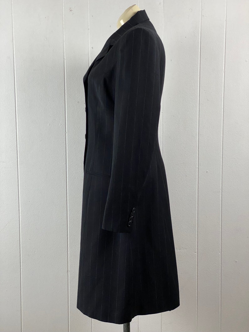 May include: A long black pinstripe blazer with a single button closure and long sleeves.
